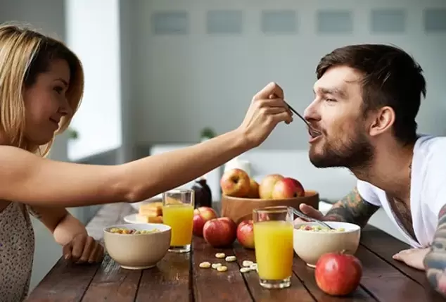 nainen ruokkii miestä pähkinöillä tehon lisäämiseksi